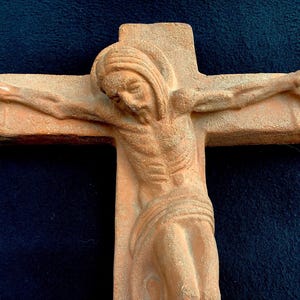 Puede incluir: Una escultura de terracota de una persona en una cruz. La escultura es detallada y muestra el cuerpo de la persona de forma realista.