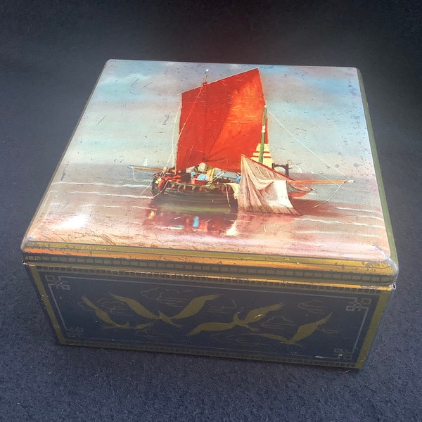 beautiful old rectangular tin with the image  of an old fishing boat with a red sail and white fishing net.