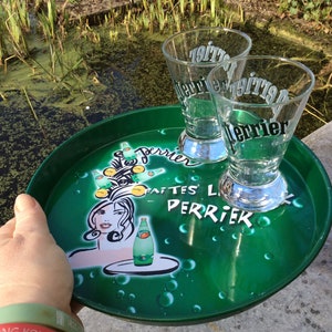 Un petit plateau de service rond vintage rétro en métal vert Perrier, design classique, déco pub, logo Perrier classique et deux verres Perrier