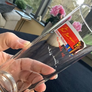 May include: A clear glass with a red and blue sticker that says "The Barman, Johnnie Walker, 'ni' mal di", with a cartoon image of a man in a blue and red shirt.