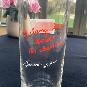 May include: A clear glass vase with the handwritten message "A classy bar knows its classics" in red ink. The signature "Johanne Walker" is written in black ink below the message.