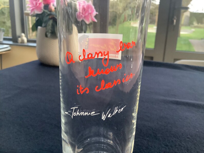 May include: A clear glass vase with the handwritten message "A classy bar knows its classics" in red ink. The signature "Johanne Walker" is written in black ink below the message.