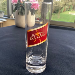 May include: A clear glass tumbler with a red and gold label that says "Johnnie Walker Red Label".