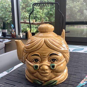 yellow glazed teapot in the shape of the head of an old lady, grandmother, made in the sixties in Japan.