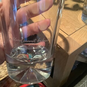 以下が含まれることがあります： 水で満たされた、テクスチャ加工された底を持つ透明なガラス。ガラスには、「Our blend cannot be beat」という文字が側面にエッチングされています。