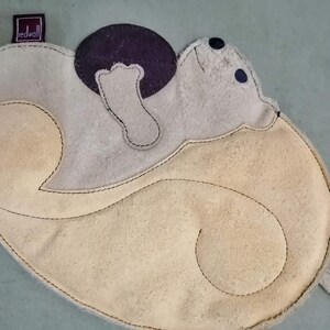 May include: A light brown leather purse with a stitched design of a bear holding a ball. The purse has a redwall label on the top.