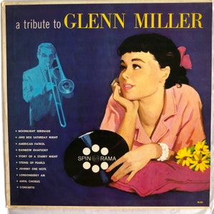 May include: A vintage vinyl record album cover featuring a woman listening to music with a pink background. The album is a tribute to Glenn Miller and features a list of songs including "Moonlight Serenade", "Juke Box Saturday Night", "American Patrol", "Rainbow Rhapsody", "Story of a Starry Night", "String of Pearls", "Johnny One Note", "Londonderry Air", "Anvil Chorus", and "Concerto". The album cover also features a black and white image of a record with the words "Spin Rama" printed on it.