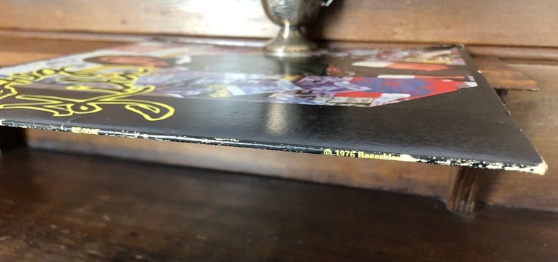 Op de afbeelding: Zwarte vinylplaat met een geel en wit ontwerp op de hoes. De tekst rechtsonder luidt "℗ 1976 Casablanca."