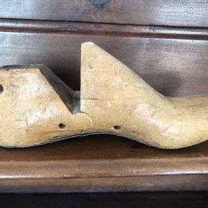 May include: A vintage wooden shoe last, used by shoemakers to shape and form shoes. The last is made of light brown wood and has a simple, classic design.