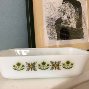 Puede incluir: Plato para hornear rectangular blanco con un diseño floral verde y amarillo. El plato tiene un borde ligeramente elevado y dos asas.