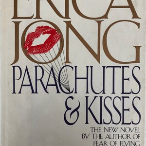 May include: A book cover with the title "Parachutes & Kisses" by Erica Jong. The cover features a red lipstick kiss with strings attached to it.