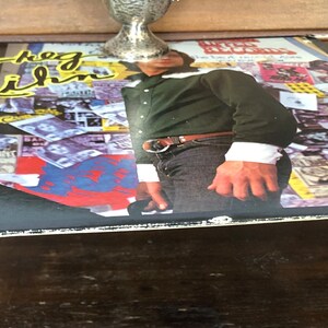 Op de afbeelding: Een zwarte vinylplaat met een collage van afbeeldingen en tekst op de hoes. De tekst op de hoes luidt "The  Last  Time".