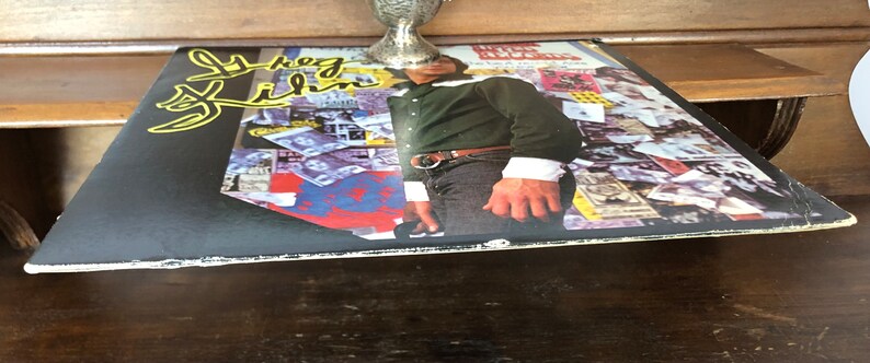 Op de afbeelding: Een zwarte vinylplaat met een collage van afbeeldingen en tekst op de hoes. De tekst op de hoes luidt "The  Last  Time".