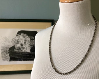 May include: A silver rope chain necklace on a white mannequin.