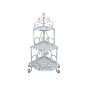 Puede incluir: Una estantería esquinera blanca de tres niveles con un marco de metal decorativo y adornado. Cada estante es triangular con un patrón tejido. La parte superior del estante tiene un remate decorativo. La estantería mide aproximadamente 61 cm de altura.