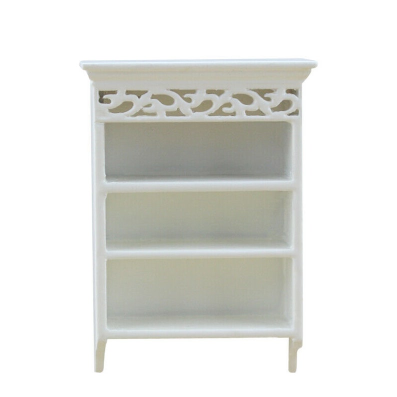 May include: White wooden bookshelf with three shelves and a decorative top. The top has a carved design.