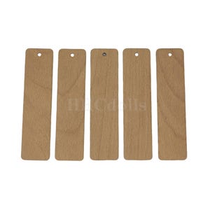 May include: Five rectangular wooden bookmarks with a natural wood grain finish. Each bookmark has a small hole at the top for attaching a string or tassel. The bookmarks are arranged vertically against a white background.