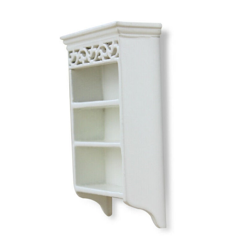 May include: White wooden wall shelf with three shelves and a decorative top. The shelf has a scalloped bottom edge.
