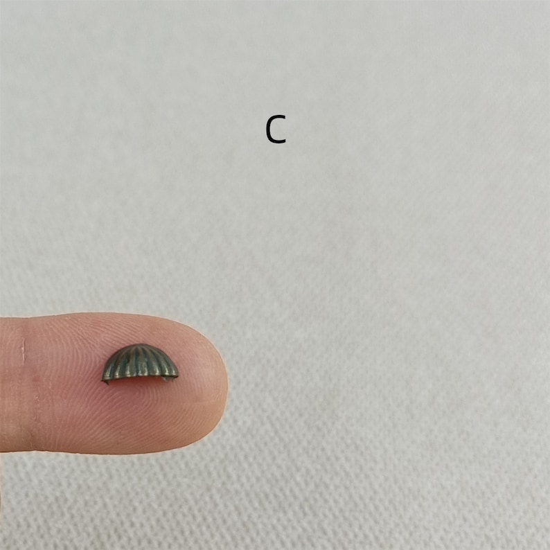 Puede incluir: Una peque&ntilde;a tapa redonda de metal con un dise&ntilde;o acanalado. La tapa es de color bronce oscuro.