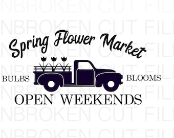 May include: A black silhouette of a pickup truck with a bed full of flowers. The text "Spring Flower Market" is above the truck and the text "Open Weekends" is below the truck. The words "Bulbs" and "Blooms" are on either side of the truck.