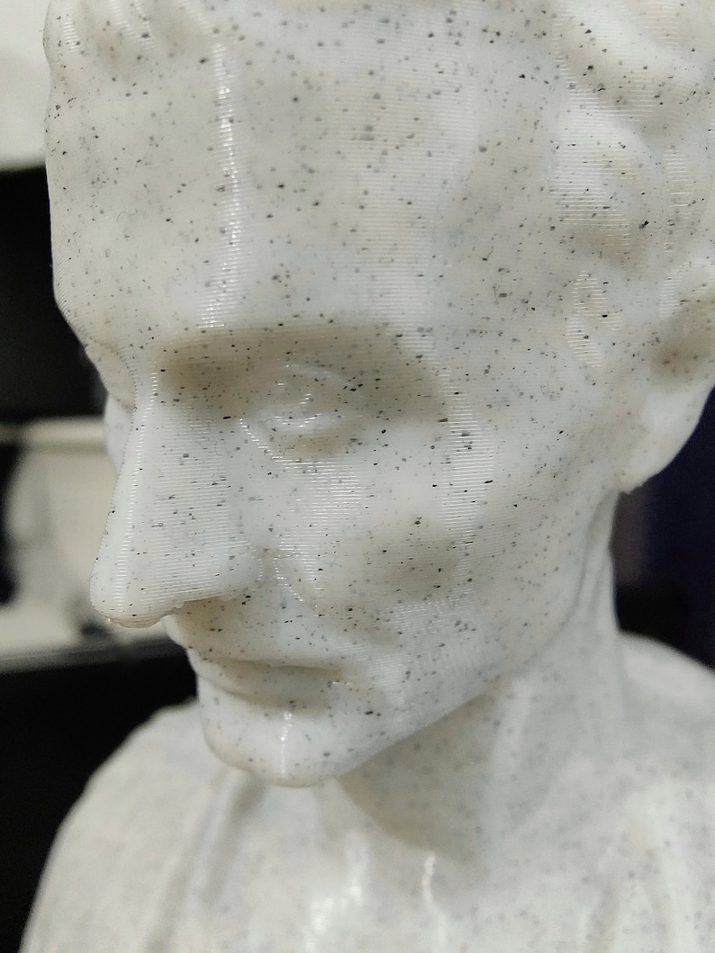 May include: A white bust sculpture of a person with a speckled finish. The sculpture is of a person's head and shoulders, and the person's face is visible. The person's mouth is slightly open, and their eyes are closed.