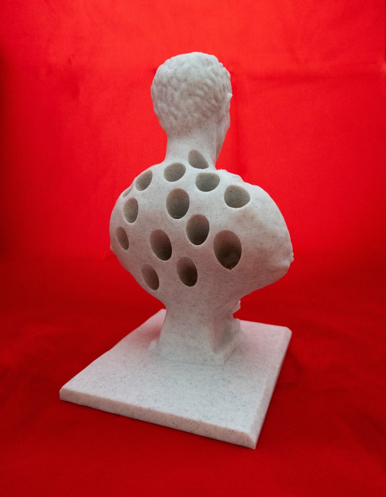 May include: White plaster bust sculpture with a detailed face and a back covered in evenly spaced circular holes.