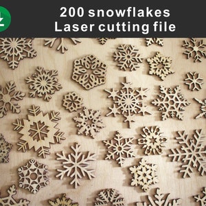 May include: A close-up of a wooden surface covered with 200 laser-cut snowflakes. The snowflakes are various sizes and designs, all with intricate details.