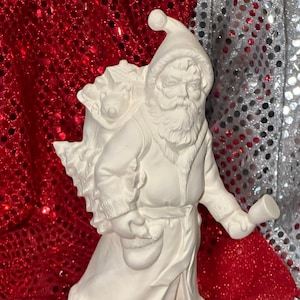 May include: White ceramic Santa Claus figurine holding a bell and a bag of gifts. The figurine is standing on a base and has a beard and a hat.