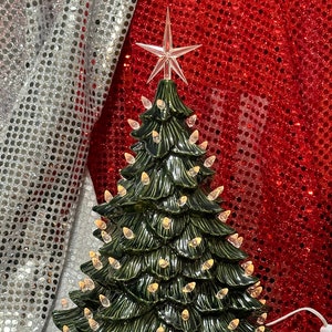 以下が含まれることがあります： 星型の飾りがついた緑色のセラミック製のクリスマスツリー。白い電球が枝に飾られています。