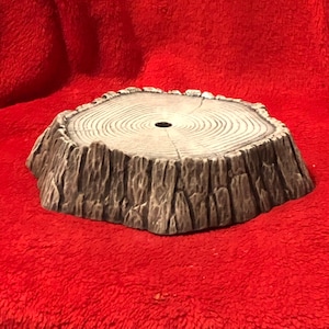 May include: A gray, textured, round tree stump base with a hole in the center. The base is made of a material that looks like wood.