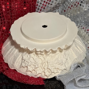 Pu&ograve; includere: Una ciotola decorativa in ceramica bianca con bordo smerlato e foro centrale. La ciotola presenta un design a foglie di agrifoglio in rilievo attorno alla base. La ciotola &egrave; probabilmente per scopi decorativi.