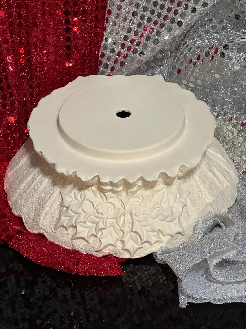 Pu&ograve; includere: Una ciotola decorativa in ceramica bianca con bordo smerlato e foro centrale. La ciotola presenta un design a foglie di agrifoglio in rilievo attorno alla base. La ciotola &egrave; probabilmente per scopi decorativi.