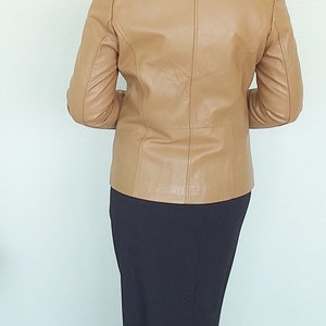May include: A tan leather jacket with a long black skirt.