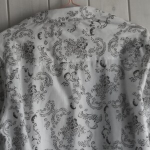 May include: White button-down shirt with a black floral pattern.