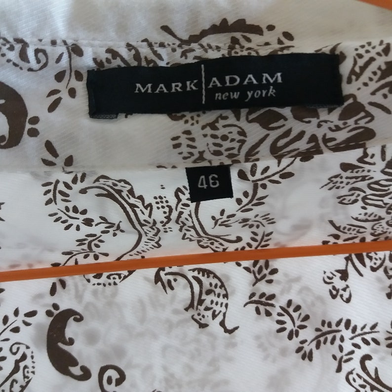 May include: White shirt with a brown paisley pattern. The shirt has a label that says "Mark Adam new york" and a size tag that says "46".