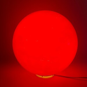 May include: A red glass sphere lamp with a yellow base.