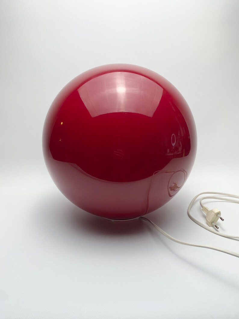 May include: A red, spherical lamp with a white cord and plug.