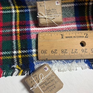 May include: Two small brown packages wrapped in twine with handwritten addresses to the North Pole. The packages are sitting on a plaid blanket with a ruler in the background.