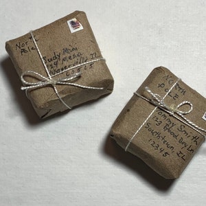 May include: Two brown packages wrapped in twine with handwritten addresses and stamps. The packages are addressed to the North Pole.