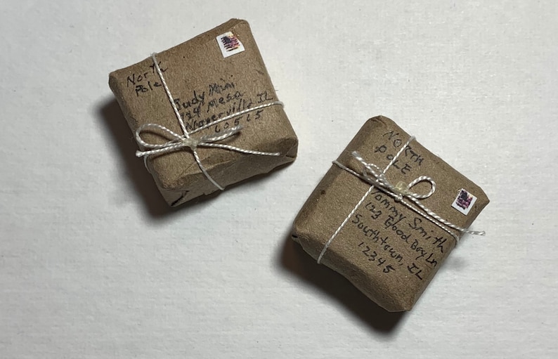May include: Two brown packages wrapped in twine with handwritten addresses and stamps. The packages are addressed to the North Pole.