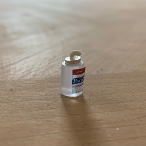 May include: A clear plastic bottle of hand sanitizer with a white pump dispenser. The bottle has a red and blue label that says "Purell Advanced Hand Sanitizer".
