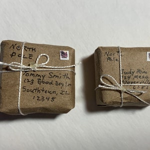 May include: Two brown packages wrapped in twine with handwritten addresses to the North Pole. The packages are addressed to "Tommy Smith, 123 Good Boy Ln, Southtown, IL 12345" and "Judy Mai, 24 Mesa, Naperville IL 60515".