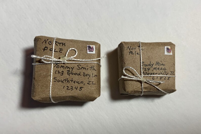 May include: Two brown packages wrapped in twine with handwritten addresses to the North Pole. The packages are addressed to "Tommy Smith, 123 Good Boy Ln, Southtown, IL 12345" and "Judy Mai, 24 Mesa, Naperville IL 60515".