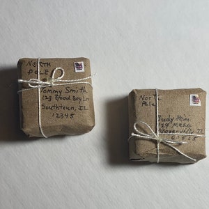 May include: Two brown packages wrapped in twine with handwritten addresses to the North Pole. The packages are labeled with names and addresses, including "Tommy Smith" and "Fudy Ma".