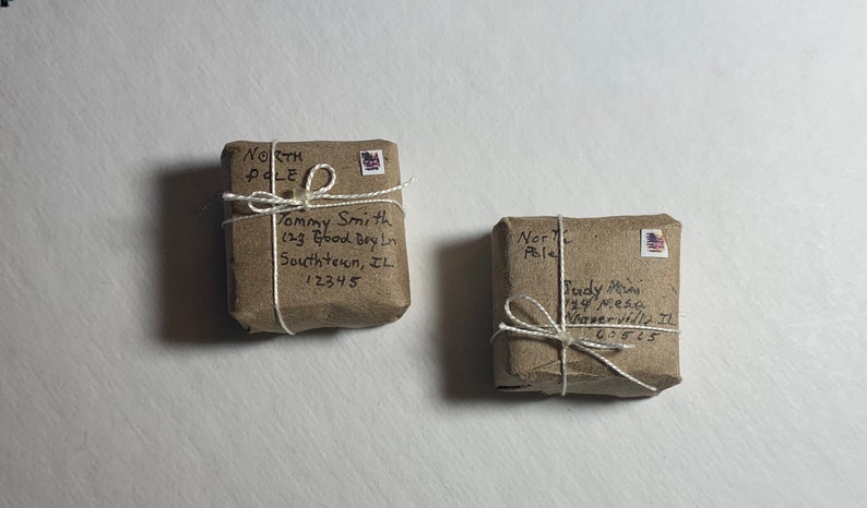 May include: Two brown packages wrapped in twine with handwritten addresses to the North Pole. The packages are labeled with names and addresses, including "Tommy Smith" and "Fudy Ma".