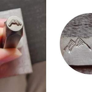 May include: Close-up of a metal stamp with a mountain range design. The stamp is used to create an impression on metal.