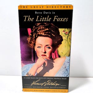 May include: A VHS tape for "The Little Foxes" starring Bette Davis. The cover features a portrait of Davis with text reading "The Great Directors" and "Samuel Goldwyn Home Entertainment". The tape is in classic black and white with the original theatrical trailer.