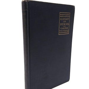 May include: A dark blue hardcover book with gold lettering on the spine. The title is "Essay on Burns" by Carlyle, published by Allyn and Bacon. The book is part of the Academy Classics series.