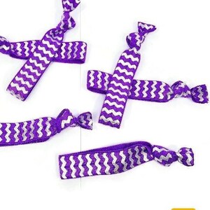 May include: Four purple and white zigzag patterned hair ties are displayed against a white background. The hair ties are knotted at the ends. The image includes the logo for TiesNSupplies.