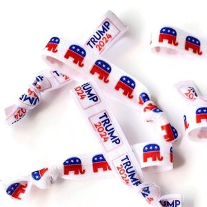 May include: A group of white elastic hair ties with red, white, and blue printed elephants and the text "TRUMP 2024".